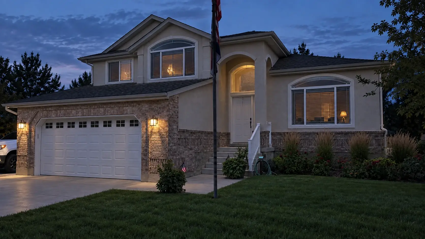 Example of a two-story stucco and brick home at dusk with no roofline lighting