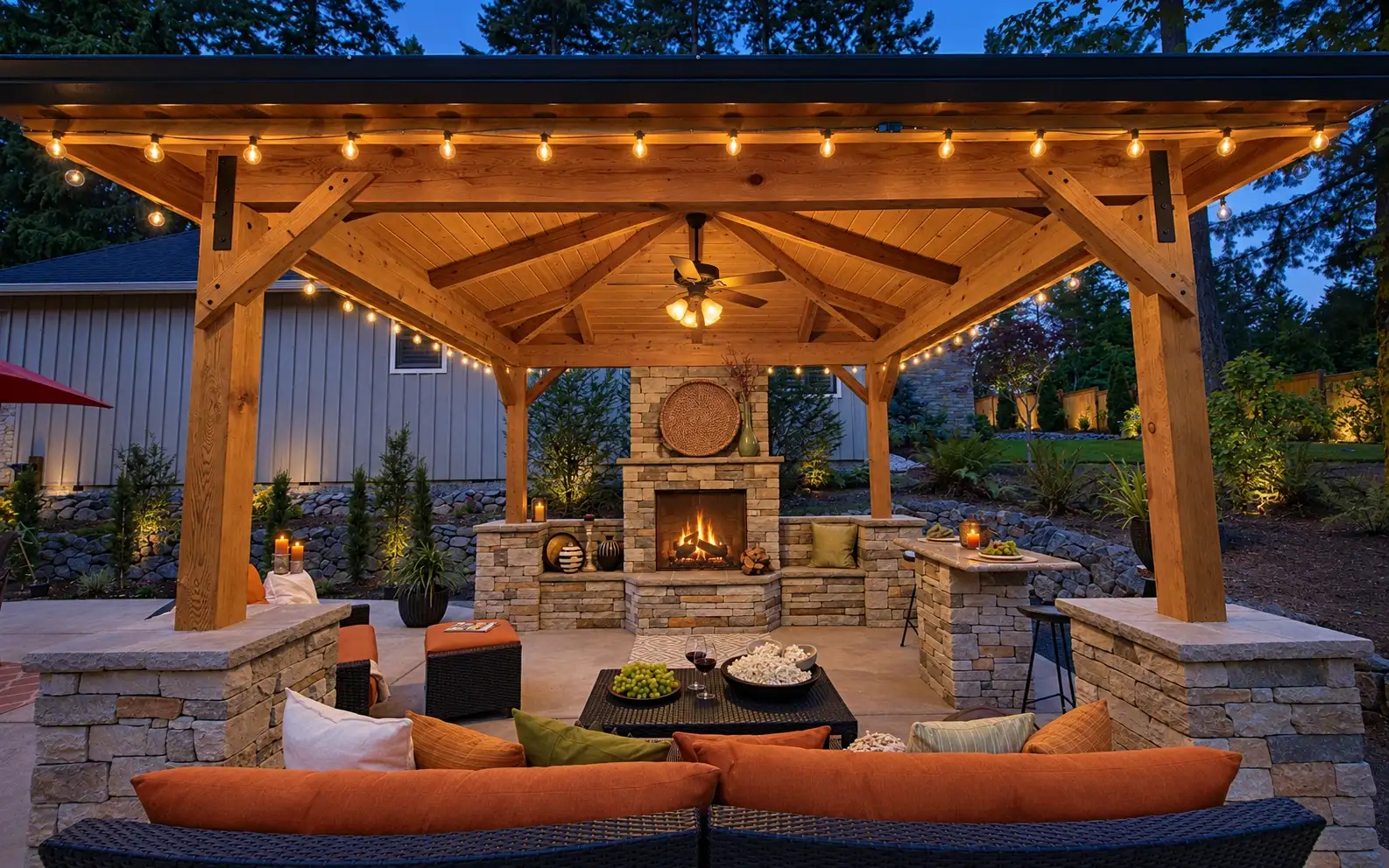 Backyard gazebo with an outdoor fireplace and warm lighting at dusk