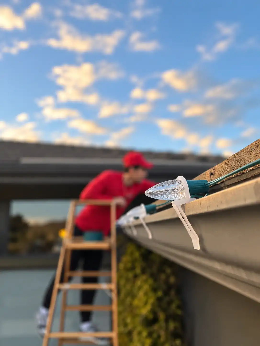 Our crew clipping warm-white C9 bulbs onto a gutter from a ladder