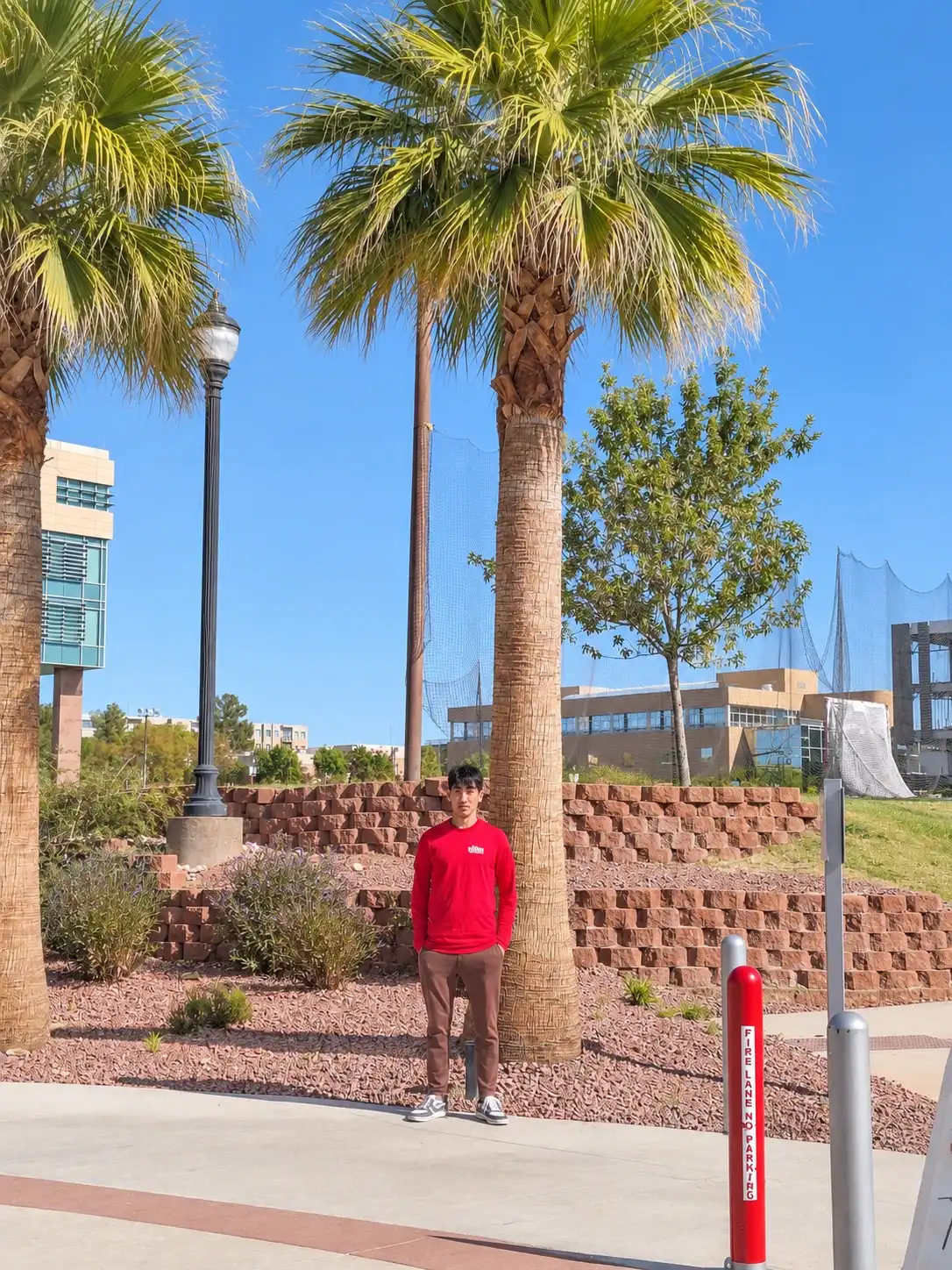 Glow Forward team member in a red branded shirt standing under palm trees
