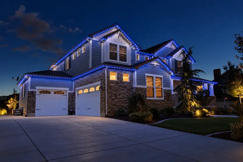 Two-story home with blue permanent roofline lighting at night
